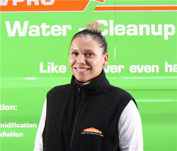 a girl in front of a green SERVPRO van