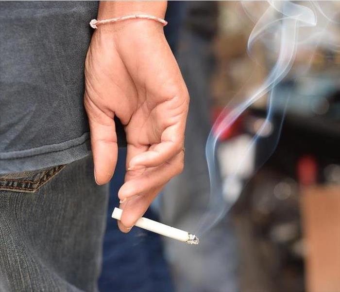 Lit cigarette held by a woman's hand.